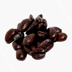A small pile of coffee beans very dark brown in colour from roasting, on a white background.